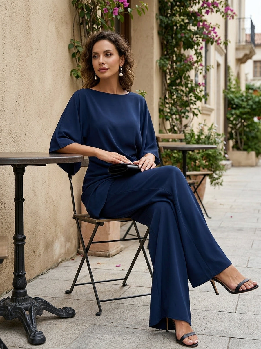Conjunto de blusa con manga capa y pantalón ancho en azul marino, sentada en una terraza